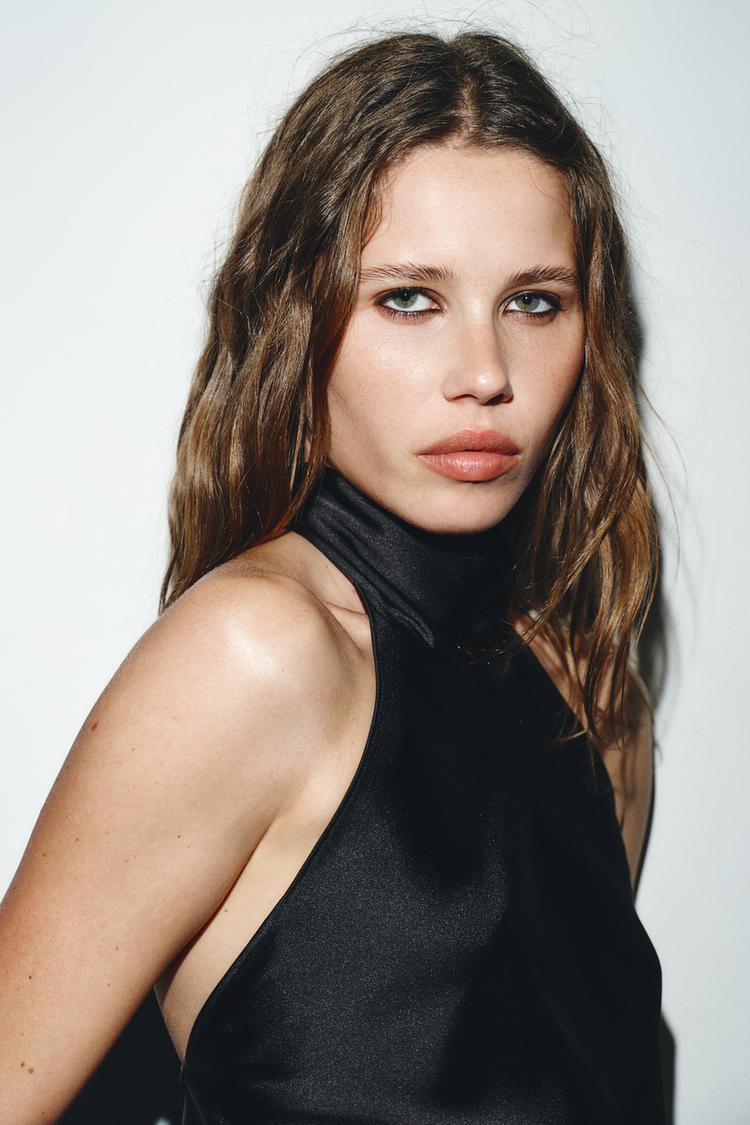 Woman wearing a black sleeveless top against a plain background