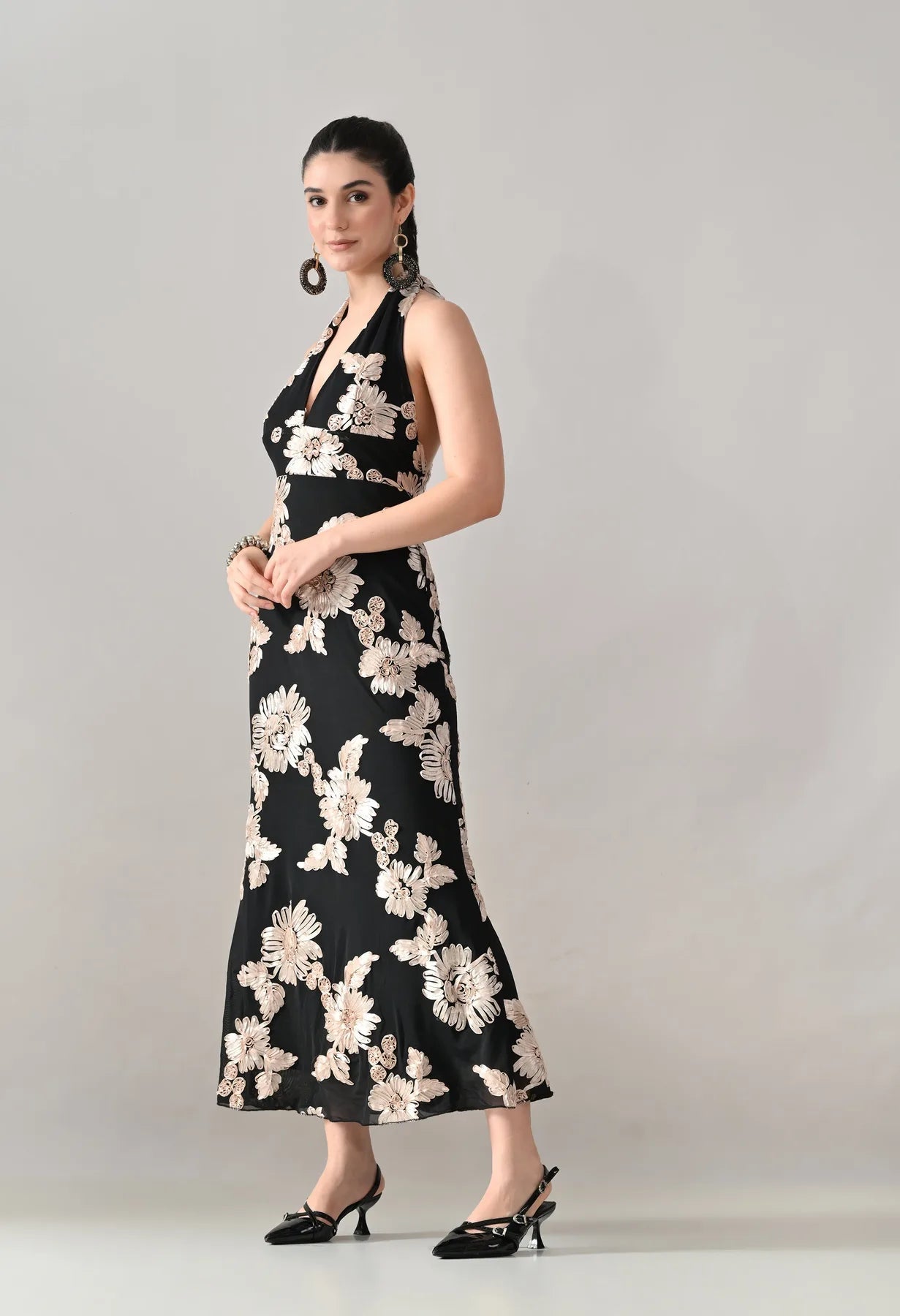 Woman wearing a black floral dress against a plain background