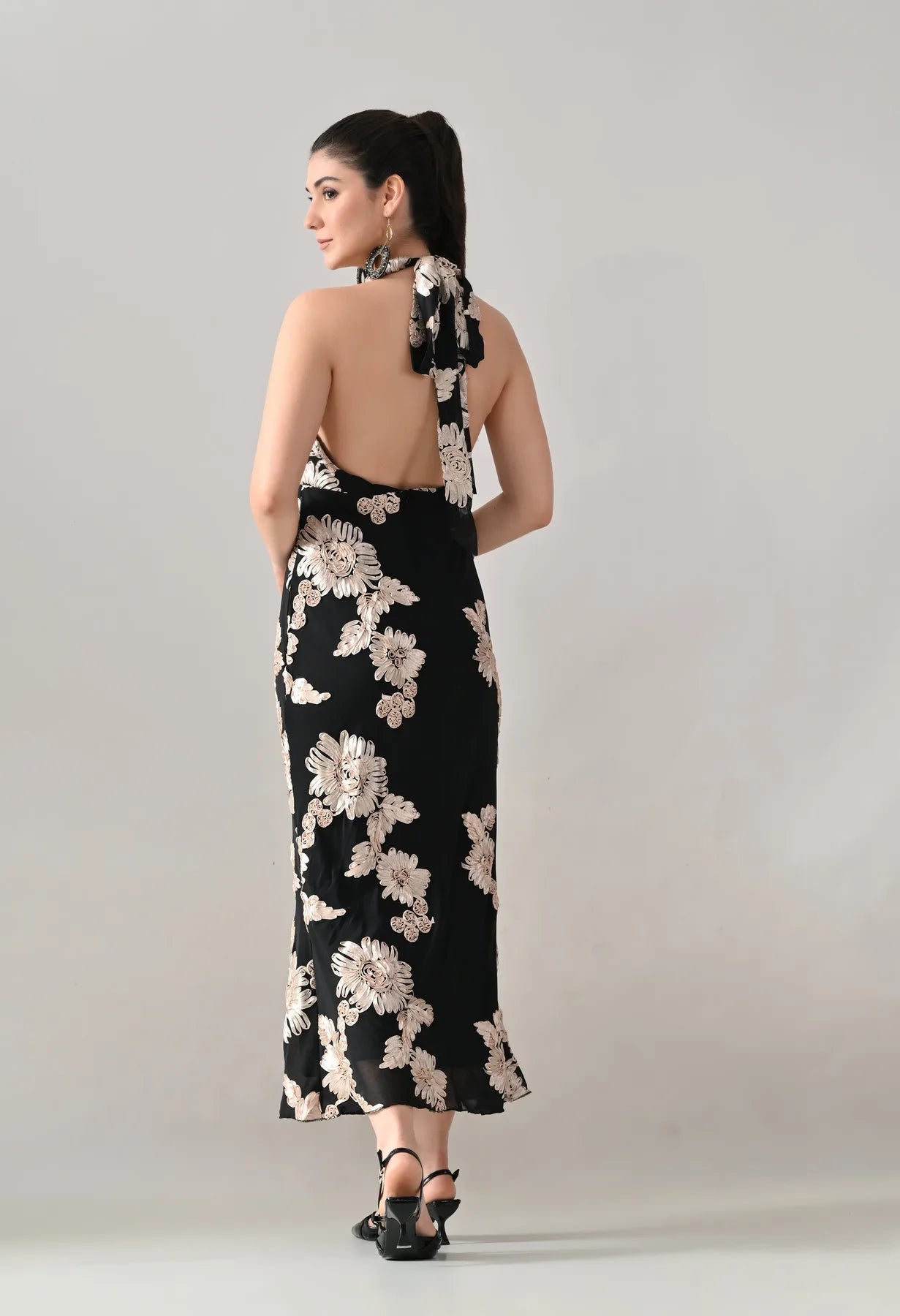 Woman wearing a black floral dress with a plain background