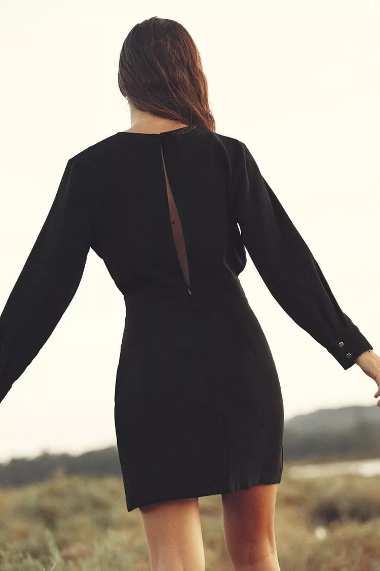 Person wearing a black dress with a cutout design in an outdoor setting